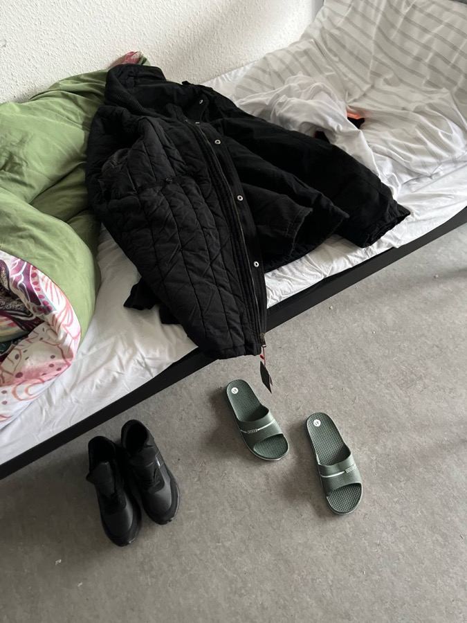 Jakna, patike i papuče na krevetu u prihvatnom kampu